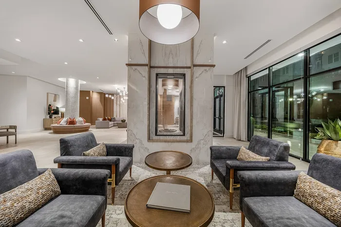 Elegant apartment lobby with chic seating, modern lighting, and a sophisticated marble centerpiece offering a luxurious ambiance.