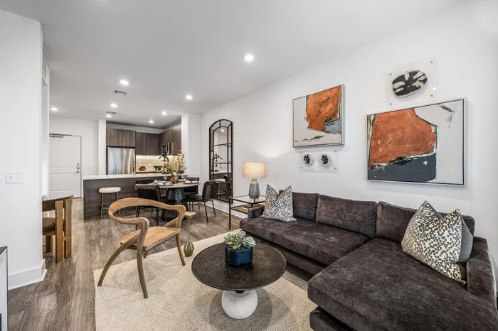 Chic modern living room with cozy sectional sofa, artistic wall decor, and stylish open-concept kitchen with elegant dining area.