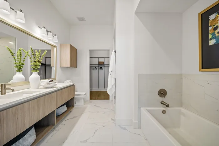 Luxurious bathroom featuring sleek double sinks, elegant marble flooring, and a spacious bathtub with modern fixtures.