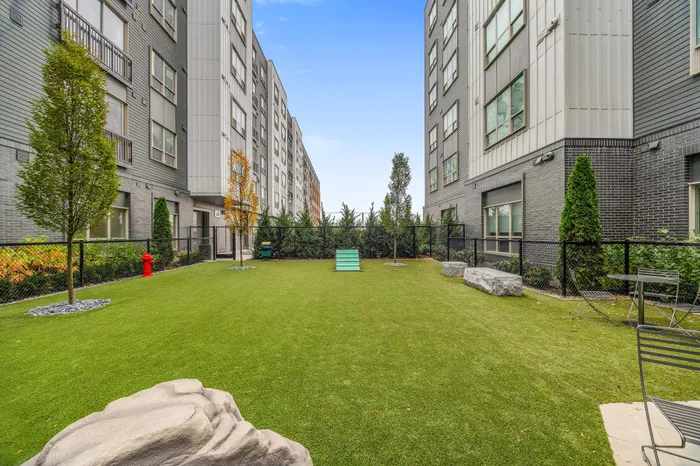 Beautiful outdoor common area with lush green lawn, surrounded by modern apartment buildings, perfect for relaxation and leisure.