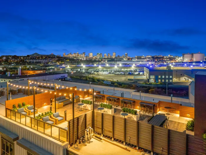 Luxurious rooftop terrace with elegant seating and vibrant city skyline views under a twilight sky, perfect for entertaining and relaxation.