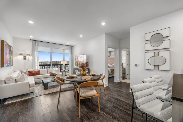 Contemporary apartment living room with elegant decor, featuring a cozy dining area, stylish sofa, and large window with scenic city views.