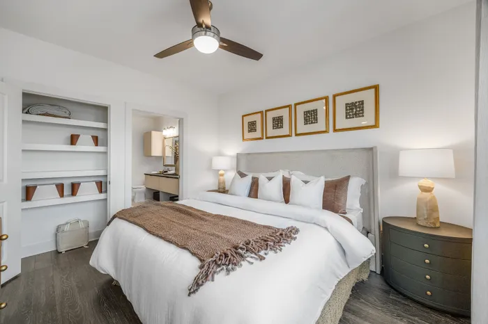 Elegant bedroom with plush bed, stylish decor, built-in shelving, and warm lighting, embodying a cozy and inviting ambiance.
