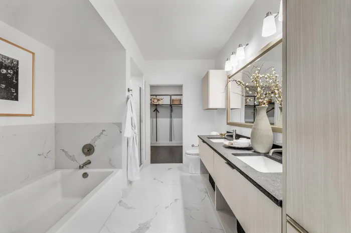 Elegant modern bathroom showcasing a luxurious marble design, dual sinks, and spacious walk-in closet.