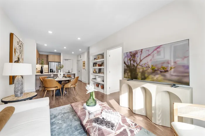 Elegant open-plan living space with a cozy lounge area, modern kitchen, and chic dining setup, enhanced by natural light and tasteful decor.