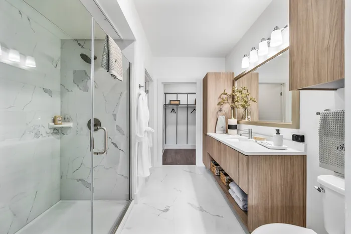 Luxurious modern bathroom with elegant marble tiles, glass-enclosed shower, and sleek wooden cabinetry.