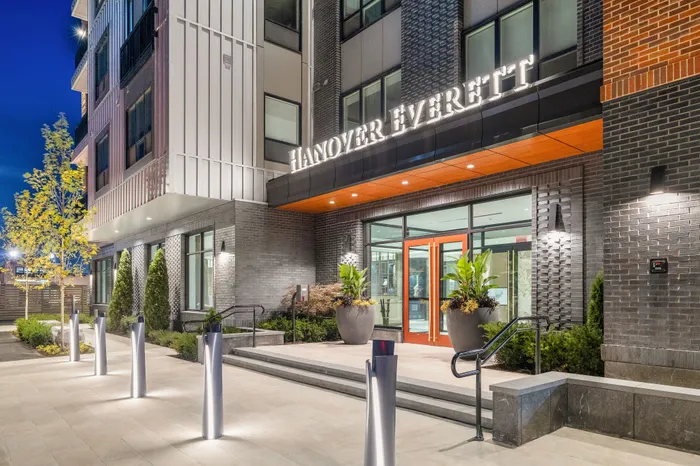 Elegant entrance of a modern apartment building with stylish lighting and lush greenery, creating a welcoming and luxurious ambiance.