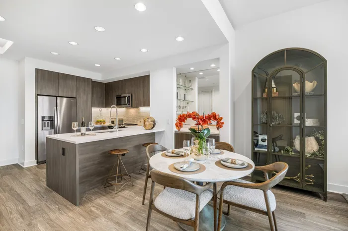 Modern kitchen and dining area with sleek cabinetry, stainless steel appliances, and elegant decor, offering a warm and inviting atmosphere.