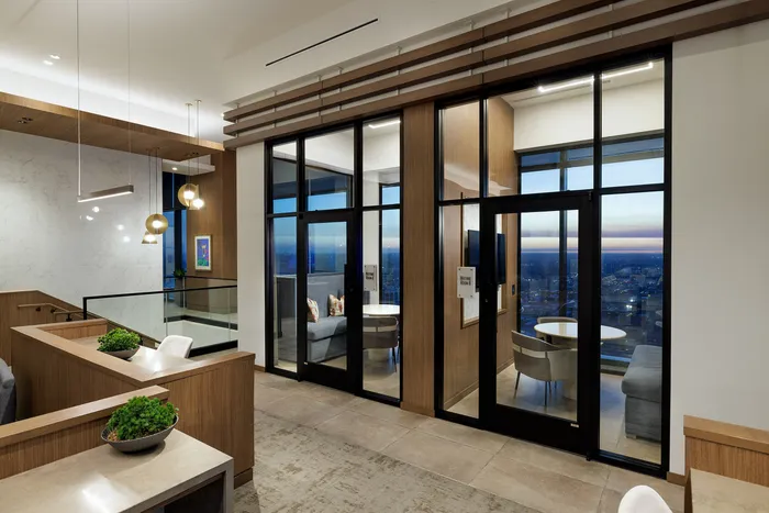 Elegant modern apartment interior featuring stylish seating area, floor-to-ceiling windows with panoramic city views, and chic pendant lighting.