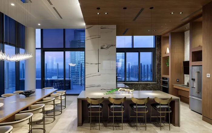 Luxurious high-rise kitchen with sleek modern design, featuring floor-to-ceiling windows, elegant pendant lights, and a spacious island, offering stunning city views.