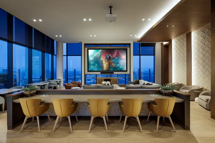 Luxurious high-rise living room with panoramic city view, featuring stylish seating, a large screen for entertainment, and modern decor.