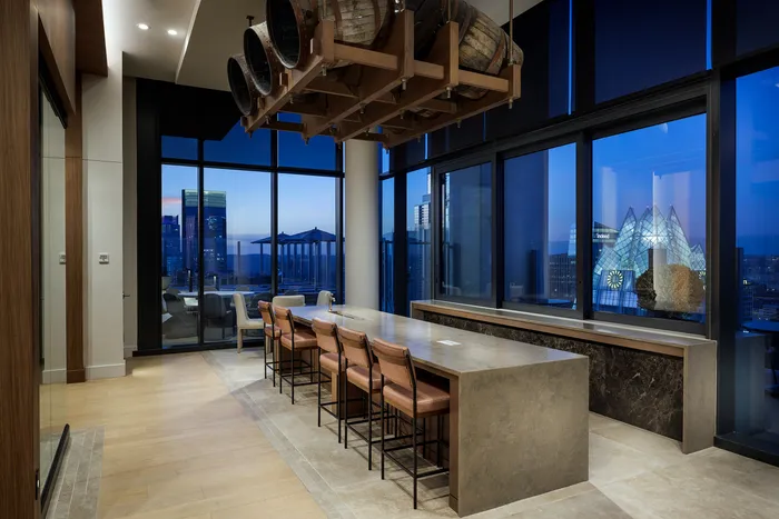 Luxurious urban dining space with a long stone countertop, chic seating, and panoramic city views through large windows.