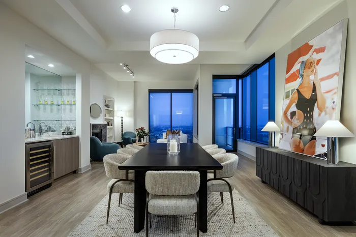 Sophisticated dining area with plush seating, modern art, and panoramic city views through floor-to-ceiling windows.