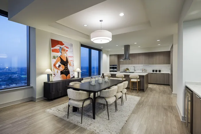 Luxurious open-plan dining and kitchen area featuring elegant wood flooring, modern cabinetry, and stunning city views.