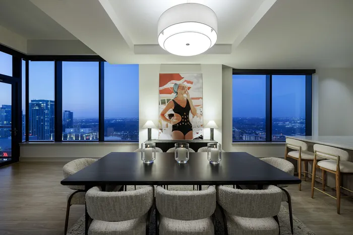 Sophisticated dining area with panoramic city views, elegant decor, and cozy seating for a luxurious apartment experience.