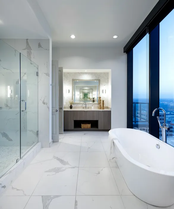 Luxurious modern bathroom with marble flooring, a sleek freestanding bathtub, and a glass-enclosed shower offering stunning city views.