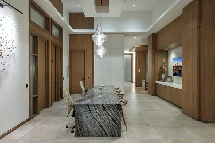 Elegant modern dining area featuring a sleek marble table, designer lighting, and rich wooden accents, perfect for entertaining in style.