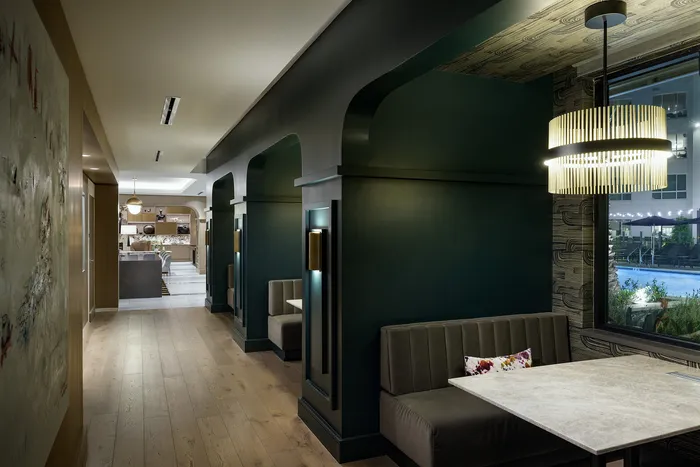 Sophisticated interior corridor with elegant lighting, modern booth seating, and a view of a luxurious outdoor pool.