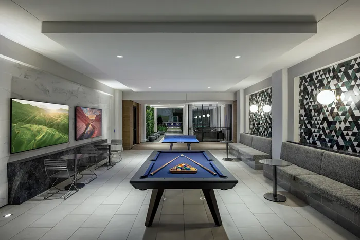 Chic recreational room with a modern pool table, sophisticated seating, and vibrant wall art creating an inviting ambiance.