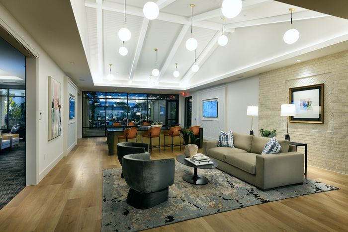 Elegant and spacious living area featuring modern lighting, plush seating, and a stylish bar area with large windows and scenic outdoor views.