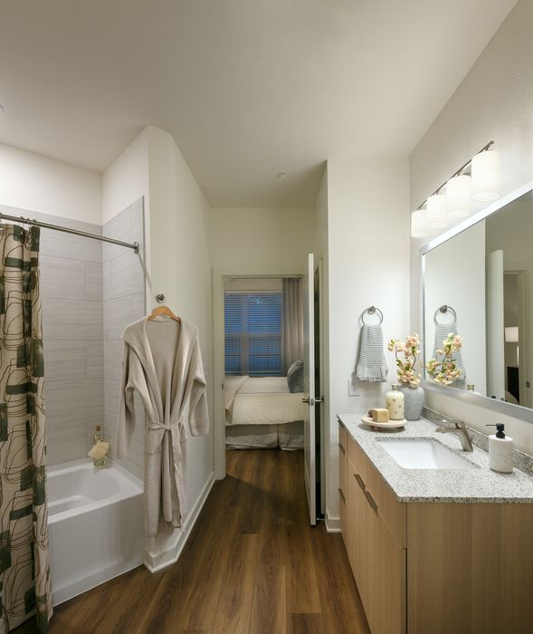 Inviting bathroom featuring a modern vanity with elegant lighting and a cozy bedroom view, highlighting a harmonious blend of comfort and style.