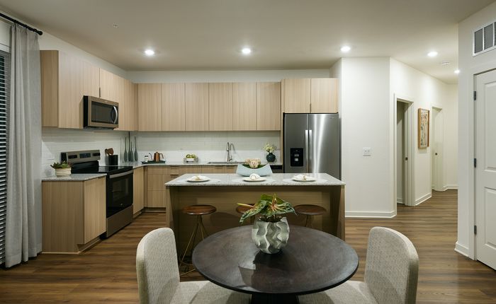 Luxurious modern kitchen with elegant wooden cabinetry, sleek stainless steel appliances, and cozy dining area with stylish decor.