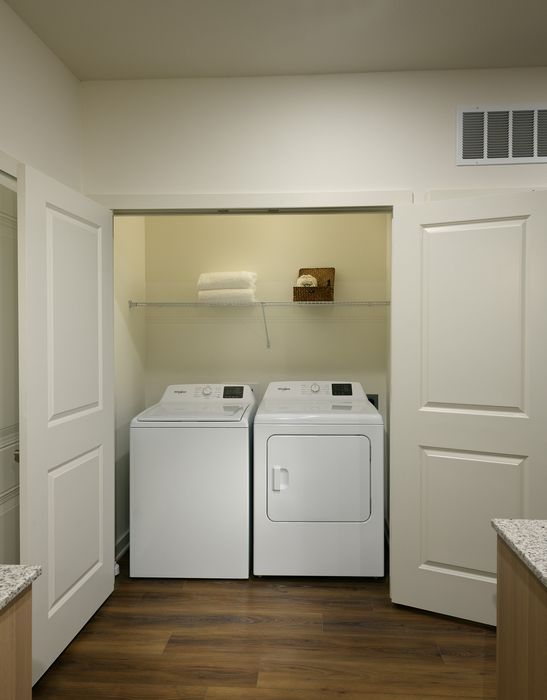 Modern laundry space with sleek washer and dryer, elegant wooden floors and open shelving for storage.
