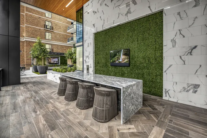 Elegant outdoor modern seating area with a sleek marble counter, surrounded by lush greenery and contemporary architecture, perfect for social gatherings.