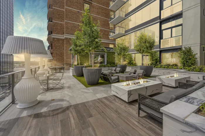 Luxurious outdoor terrace featuring elegant seating with fire pits, modern decor, and lush greenery, ideal for relaxation and entertainment.