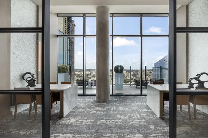 Modern high-rise common area with panoramic city views, elegant marble tables, and stylish decor.