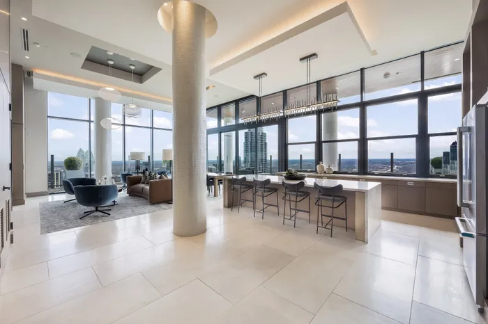 Luxurious open-concept apartment living room with panoramic city views, modern furnishings, and a sleek kitchen island.