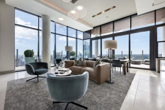 Spacious luxury apartment living room with elegant furnishings, floor-to-ceiling windows, and breathtaking city views.