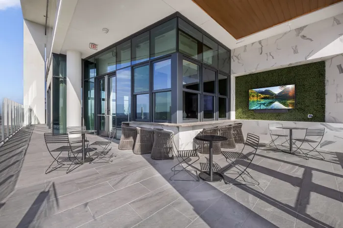 Stunning rooftop terrace with modern seating, panoramic glass windows, and lush green accent wall, perfect for relaxation and entertainment.