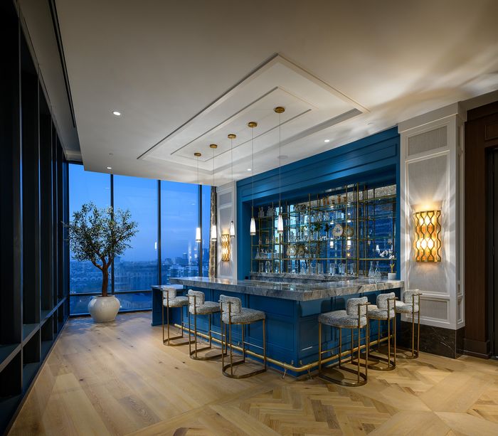 Luxurious home bar with elegant counter, chic bar stools, and large windows offering stunning city views.