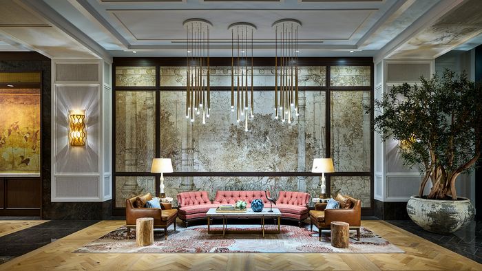 Luxurious hotel lobby featuring elegant lighting, plush seating, and stylish decor with a vintage mural backdrop.