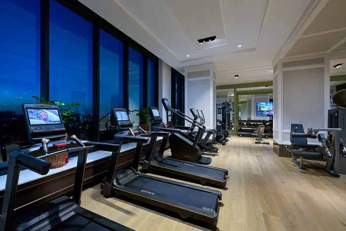Luxurious home gym with state-of-the-art treadmills and panoramic city views through floor-to-ceiling windows.