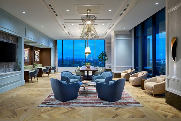Luxurious apartment lounge with modern blue armchairs, elegant dining area, large windows with stunning views, and stylish lighting.
