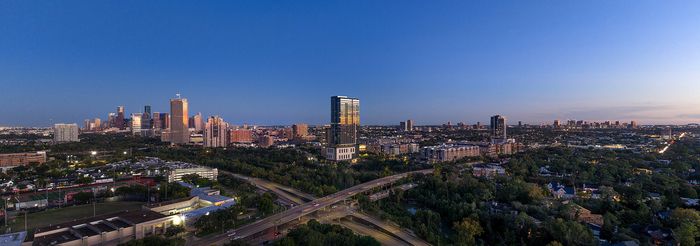 Stunning panoramic cityscape view at dusk showcasing a vibrant skyline and lush greenery.