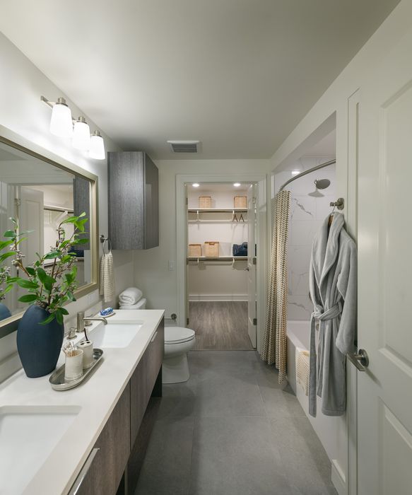 Luxurious bathroom featuring sleek double vanities, modern fixtures, and an elegant walk-in closet.