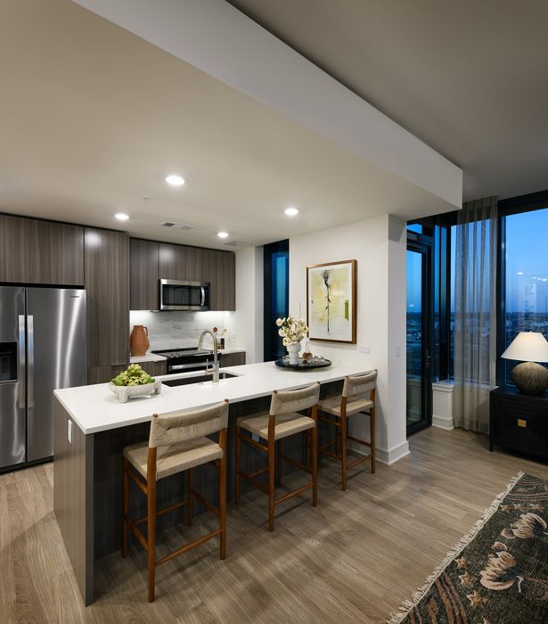 Modern kitchen with sleek cabinetry, stainless steel appliances, and elegant island seating for three, offering a cozy dining area.