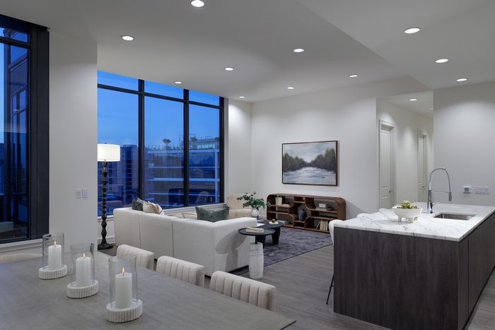 Luxurious open-concept living space with panoramic city views through floor-to-ceiling windows, featuring a stylish dining area and modern kitchen with sleek finishes.
