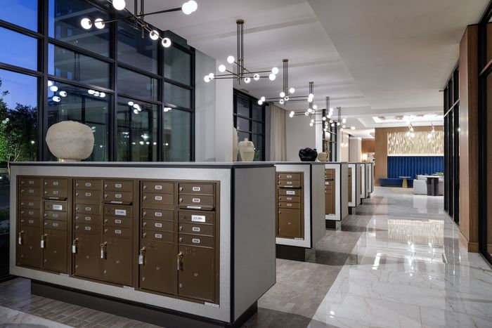 Sleek apartment lobby with modern mailbox setup, glossy floors, and elegant lighting fixtures.