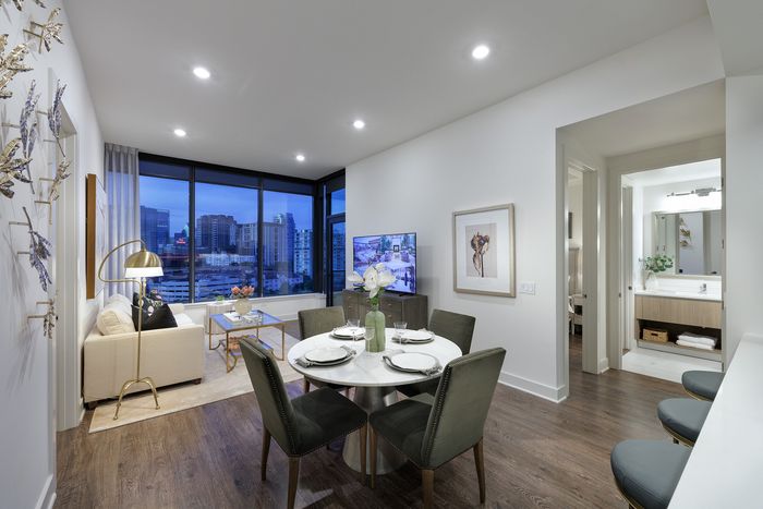 Modern urban apartment with open dining and living area, stunning city views, and elegant decor.