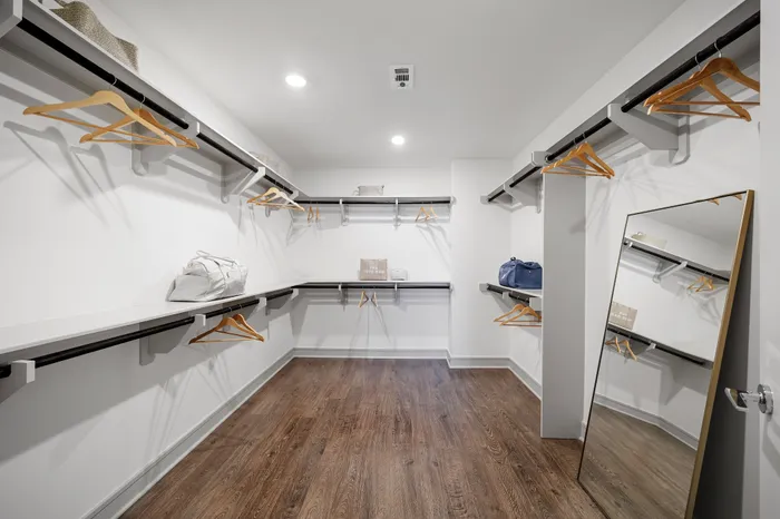 Spacious walk-in closet with elegant wood flooring, modern shelving, and ample hanging space, perfect for a luxurious lifestyle.