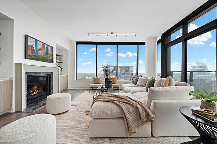 Luxurious living room with panoramic city views, elegant fireplace, and chic modern d&eacute;cor.