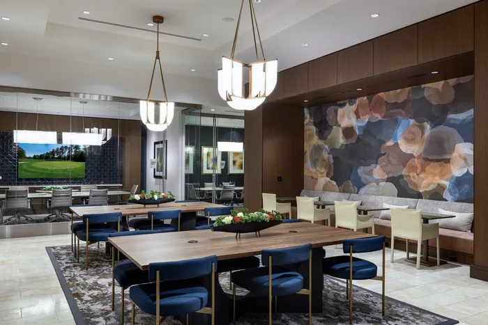 Luxurious dining area with modern chandeliers, stylish wooden tables, and elegant blue chairs, complemented by a vibrant abstract mural.