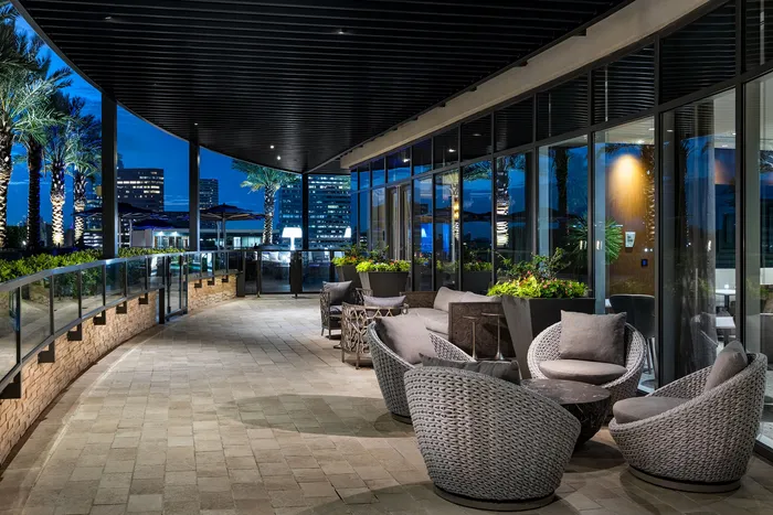 Luxurious outdoor terrace with stylish seating and vibrant plant decor, set against a stunning city skyline at night.