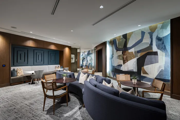 Modern lounge area with chic curved sofas, stylish abstract wall art, and a cozy seating arrangement.