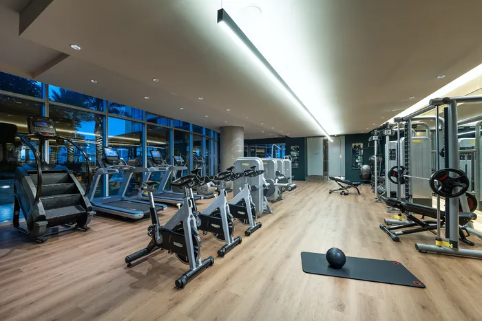 Modern gym facility with state-of-the-art exercise equipment, offering an inviting workout environment with floor-to-ceiling windows.