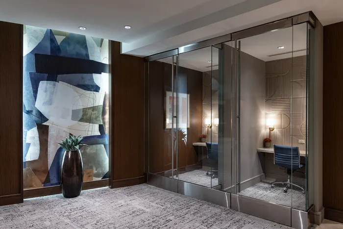 Elegant lobby area with modern artistic wall design, glass partitions, and a cozy workspace with stylish lighting.